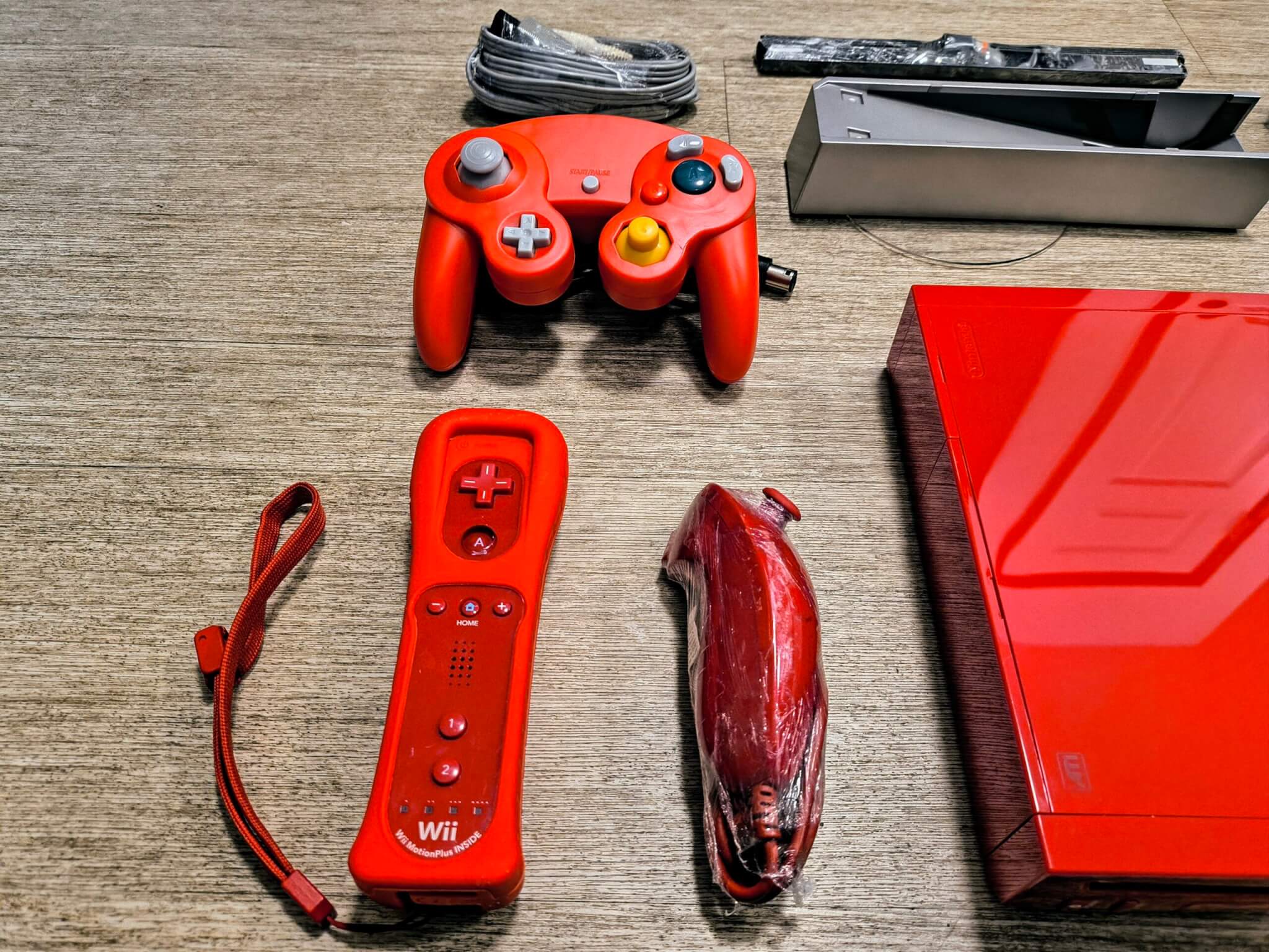 Big Bonus! Ships With An Authentic Nintendo Near New Condition Red Motion Plus Remote With Grip, Strap, and NunChuk. We Also Include A New Red After Market GameCube Controller.